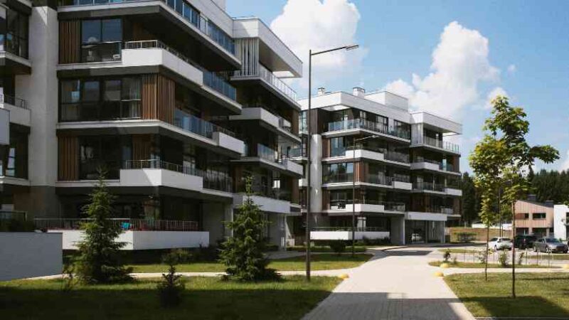 Modern apartment buildings surrounded by greenery, representing sustainable urban architecture aligned with WELL Building principles focused on occupant health and wellness.