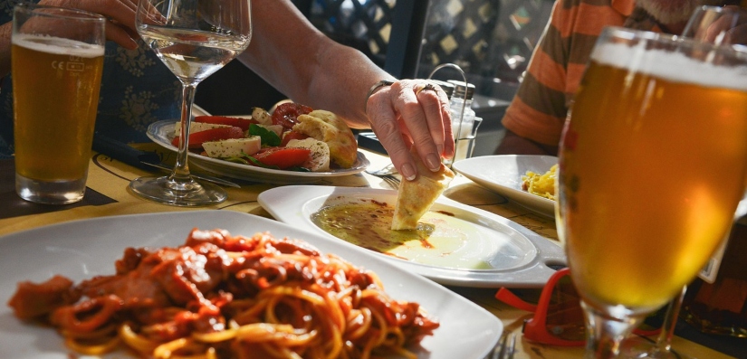 A group of people enjoying a meal together at a dinner table, featuring a variety of dishes and drinks.