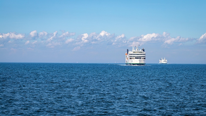 A white ferry is approaching the port, sailing on the open sea.