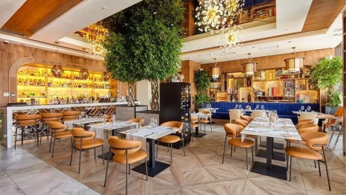 Modern and inviting dining area at Marea Restaurant, Porto Montenegro, with elegant table settings, warm lighting, greenery accents, and a refined Mediterranean ambience.