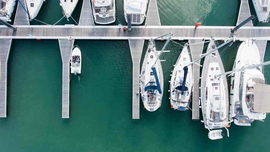 Anchored yachts lined along a marina dock during calm weather, showcasing safe yacht docking and mooring practices.