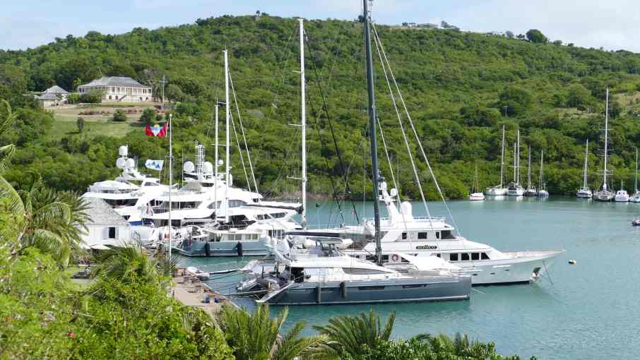 Tropical bay with several yachts anchored off a green island.