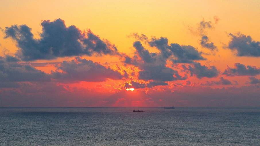 Vibrant sunset over a calm sea with colourful clouds on the horizon.
