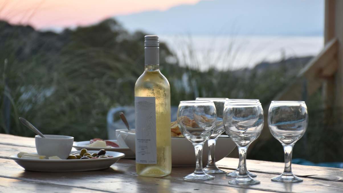 Bottle of white wine and four glasses with a sea view in Montenegro.