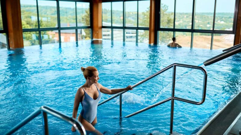 High-angle view of a woman exiting a spa pool at a luxury wellness resort.