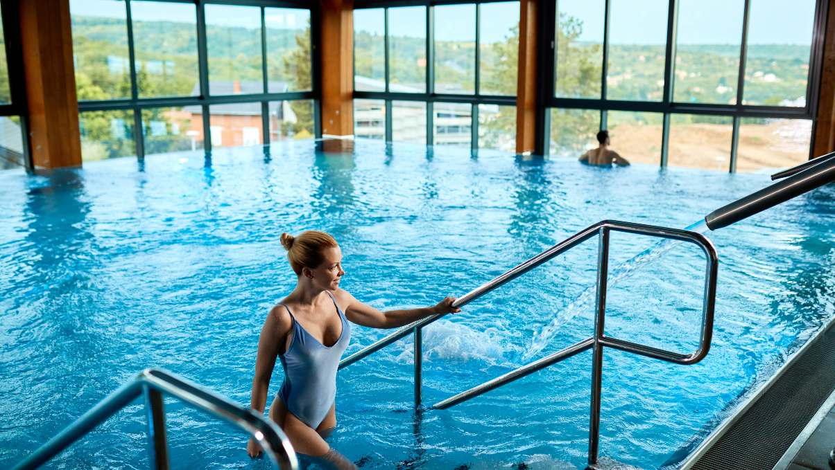 High-angle view of a woman exiting a spa pool at a luxury wellness resort.