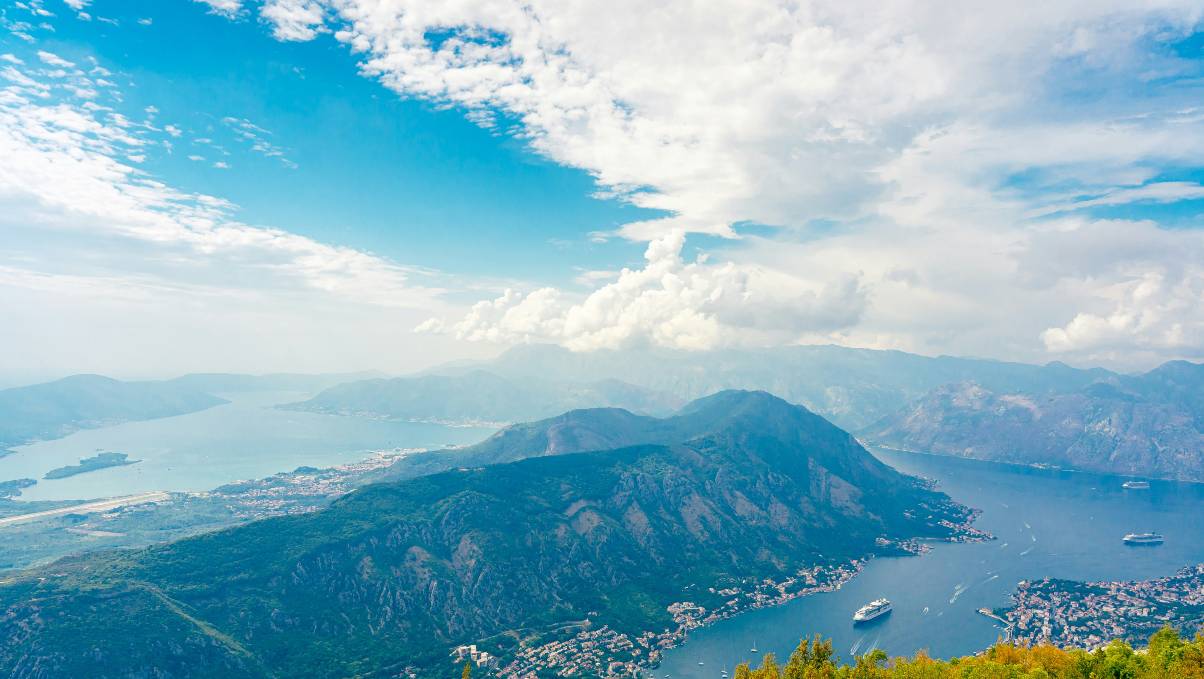 Bay of Kotor coastline with calm Adriatic water and mountains in the background.