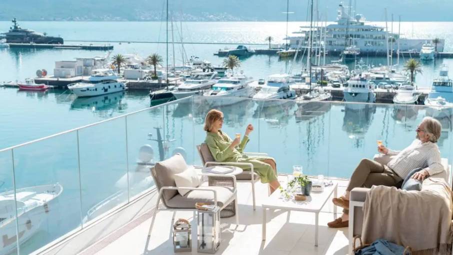 Couple relaxing on a waterfront balcony overlooking the Porto Montenegro marina in Tivat.